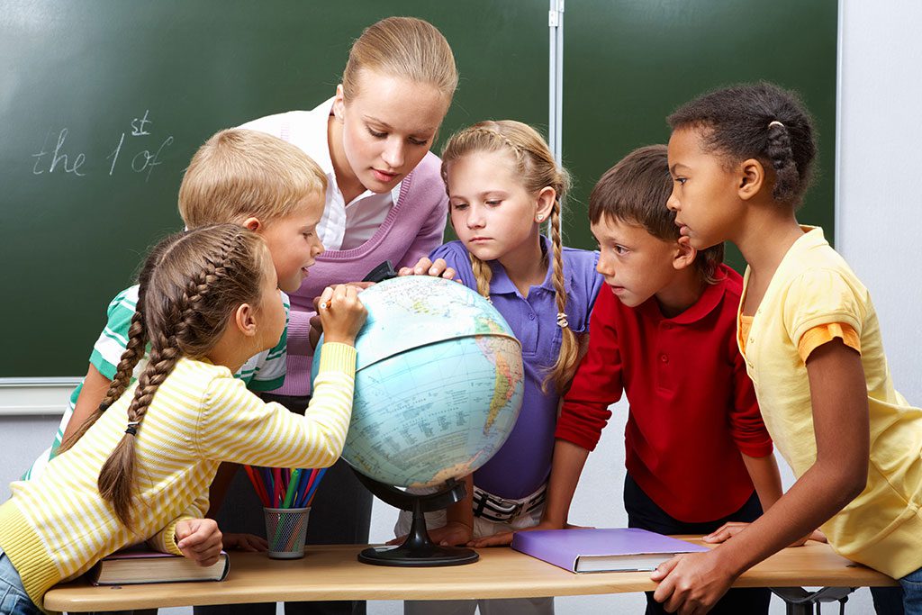 portrait-of-pupils-looking-at-globe-while-listening-to-teacher-during-geography-lesson