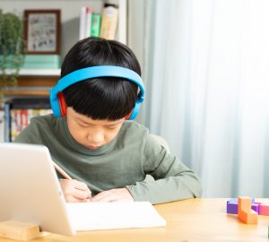 Portrait of smart Asian student boy with headphone, write, study
